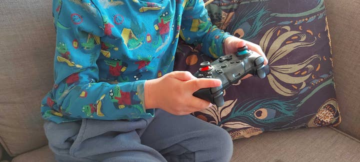 A child sitting on a couch holding a controller